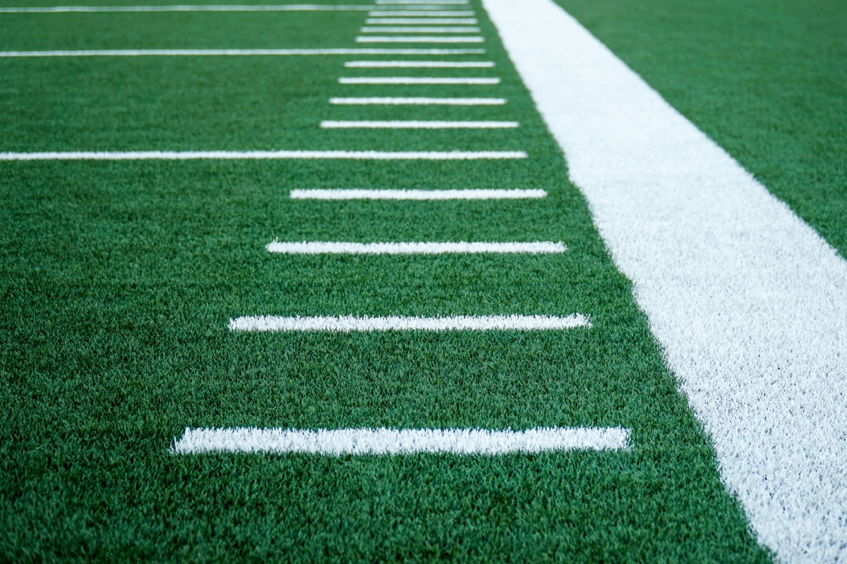 Football field artificial turf with precise yard line markings showing professional maintenance quality